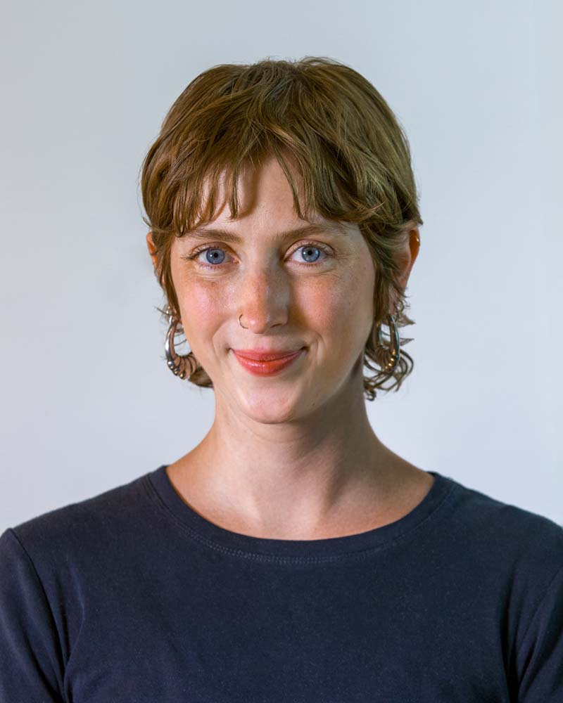 Image: Circular cropped photo of Beth McKenney: A white woman with short brown hair and blue eyes, wearing a white button-down shirt.