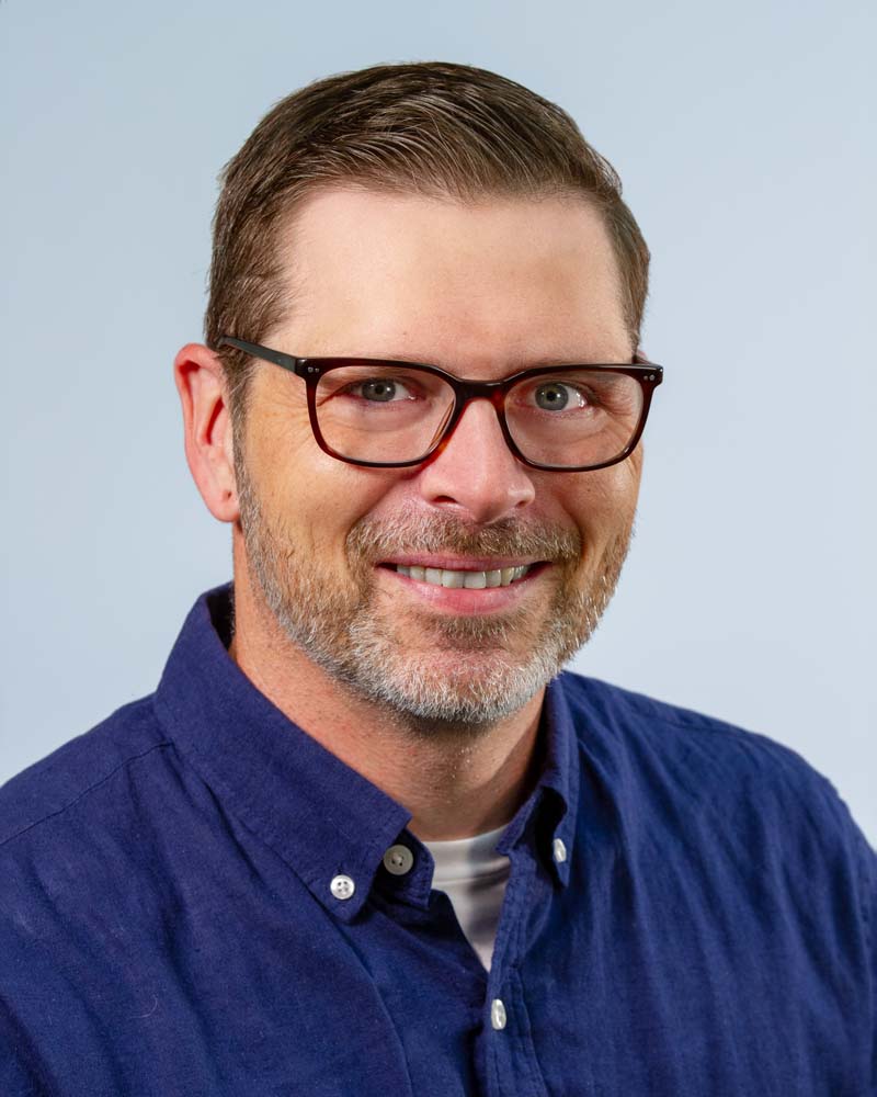 Image: Andrew Coltrin, white male with graying hair and glasses, smiling in his home office.