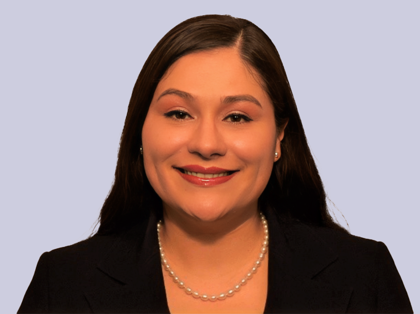 Image: Circular headshot of Amy Gonzalez, a Latina Woman with dark hair with a dark blazer and a pearl necklace.