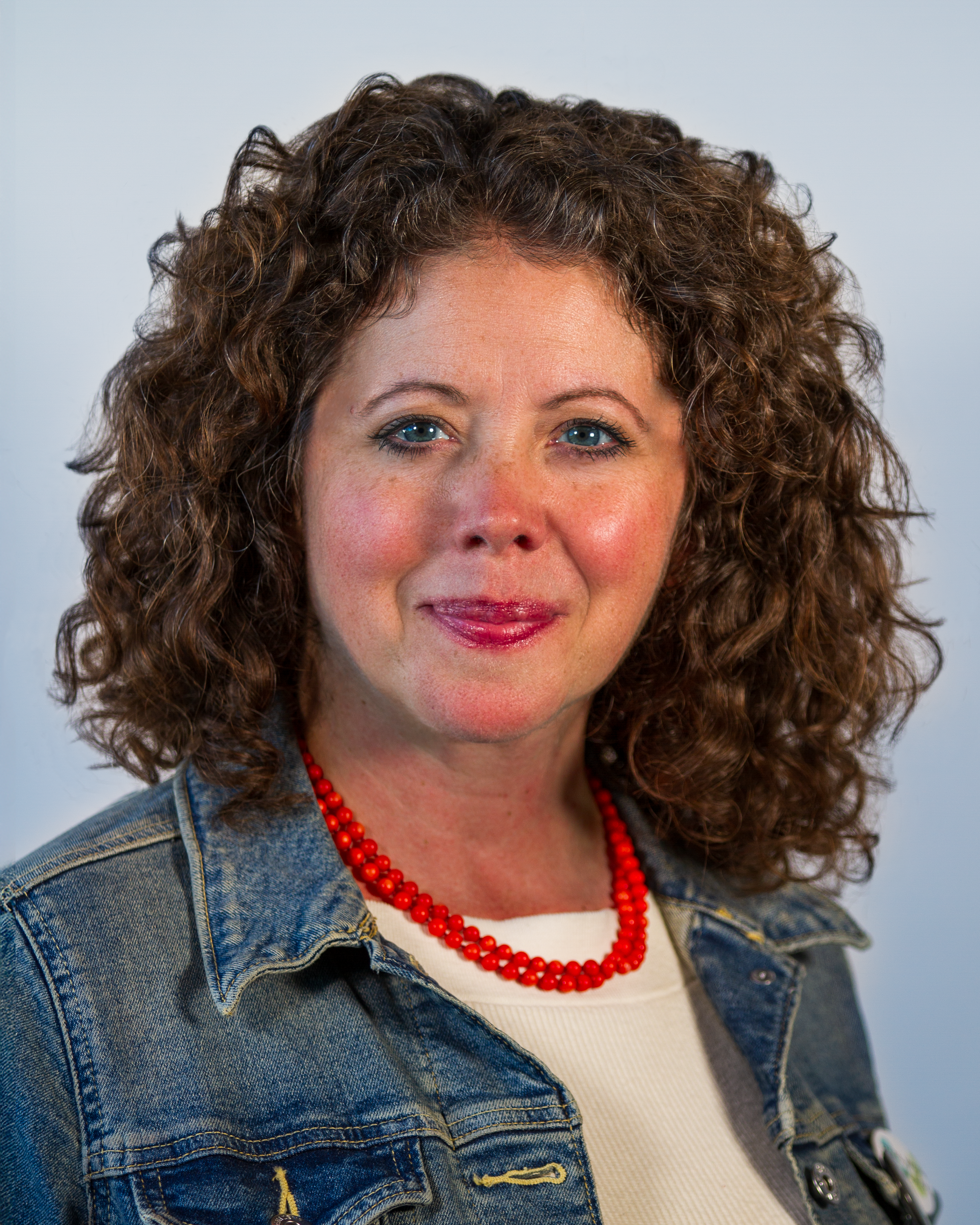 Image: Headshot of Heather Evans, a white woman with curly, brown, shoulder length hair & blue eyes, wearing a white button down shirt and a necklace.