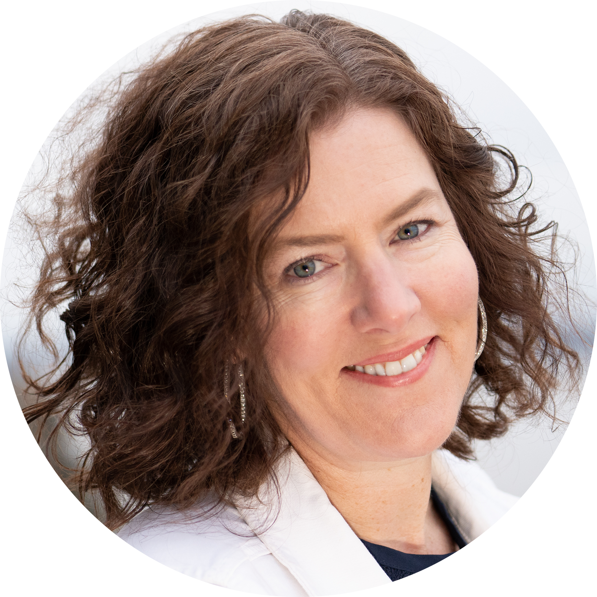 Image: Photo of Lisa Latchford, a white woman with curly brown hair wearing a white jacket and dark shirt. The background is out of focus, highlighting the subject's hair and clothing.