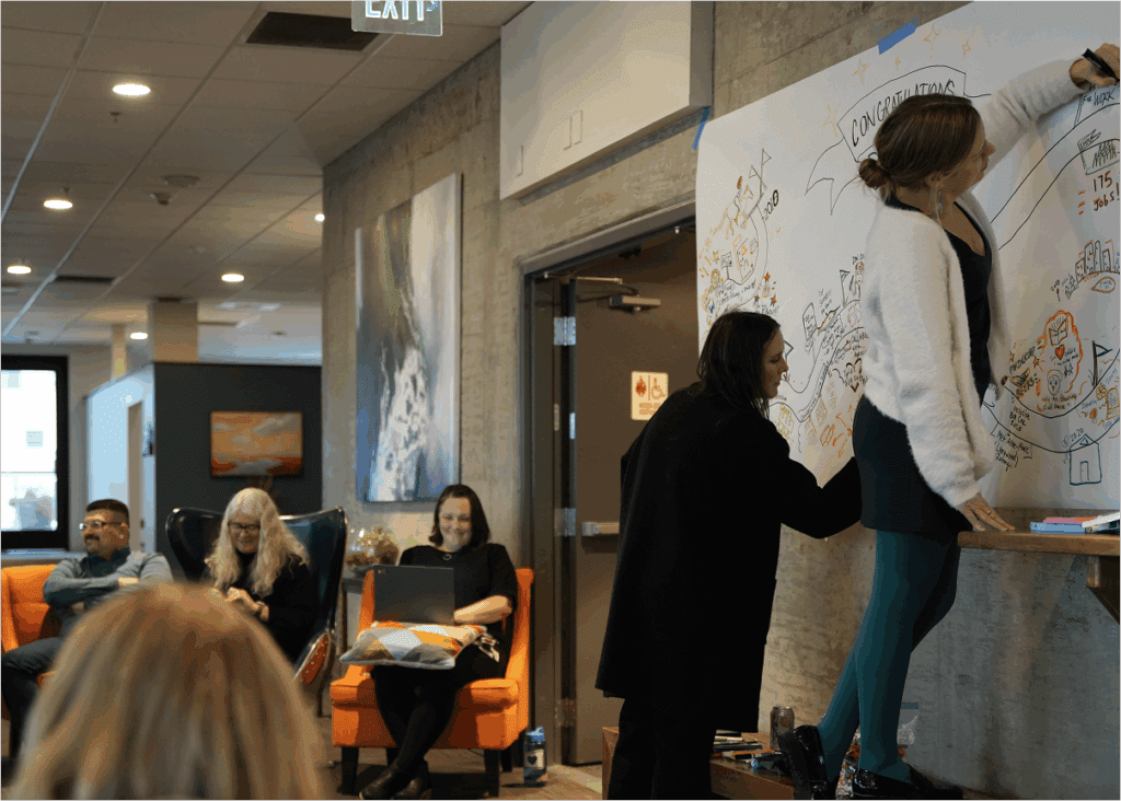 Wise employees drawing graphics and visuals on a large piece of paper with markers.