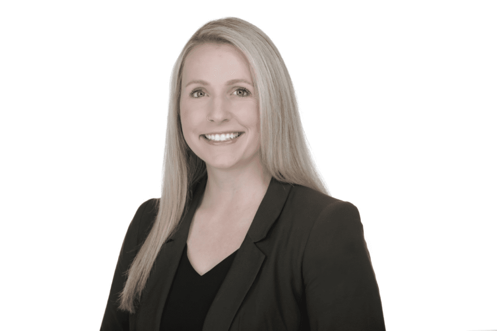 Blonde, Caucasian woman smiling wearing a blazer with a white background.